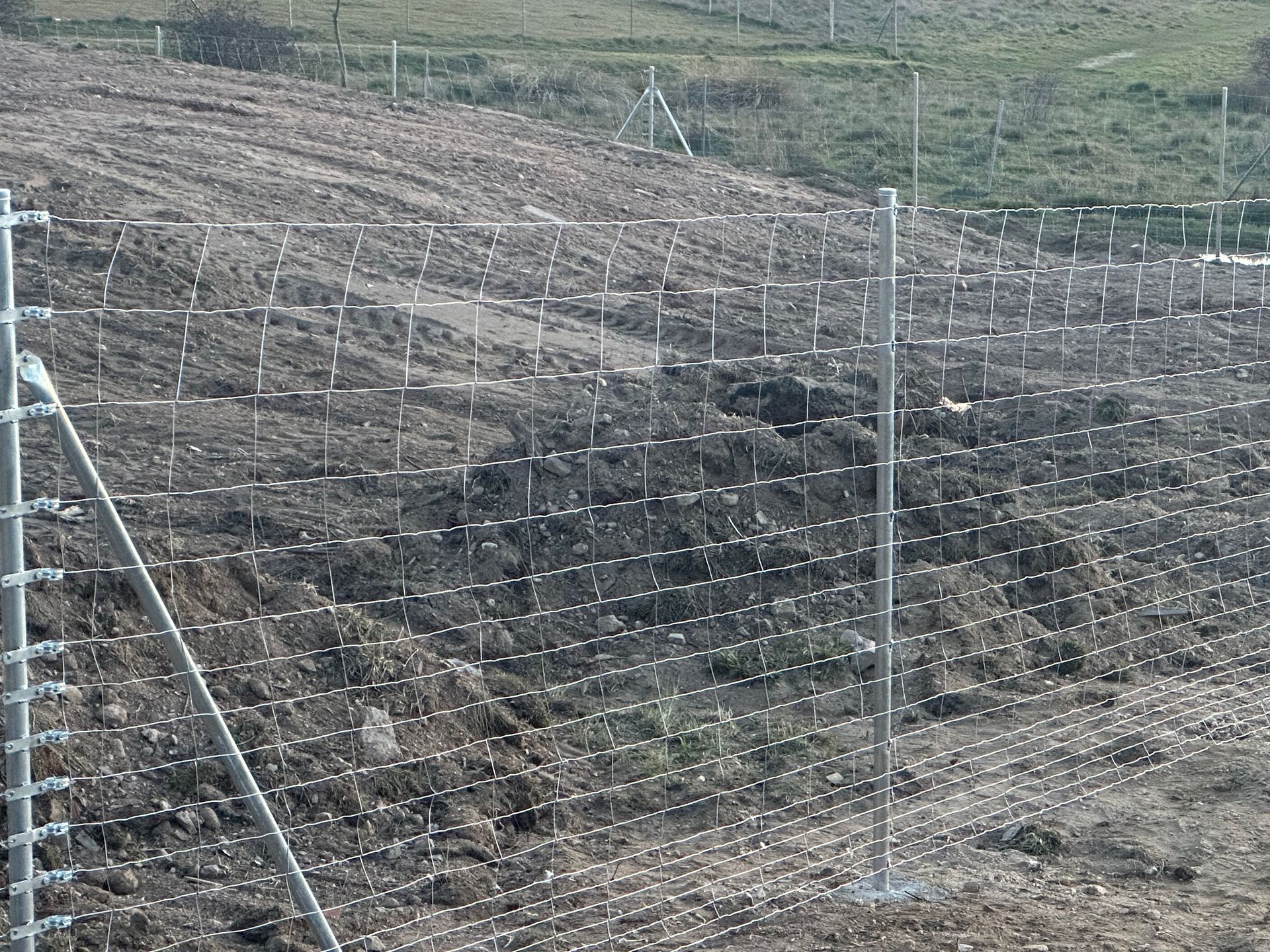 Una valla rodea un campo de tierra y hierba.