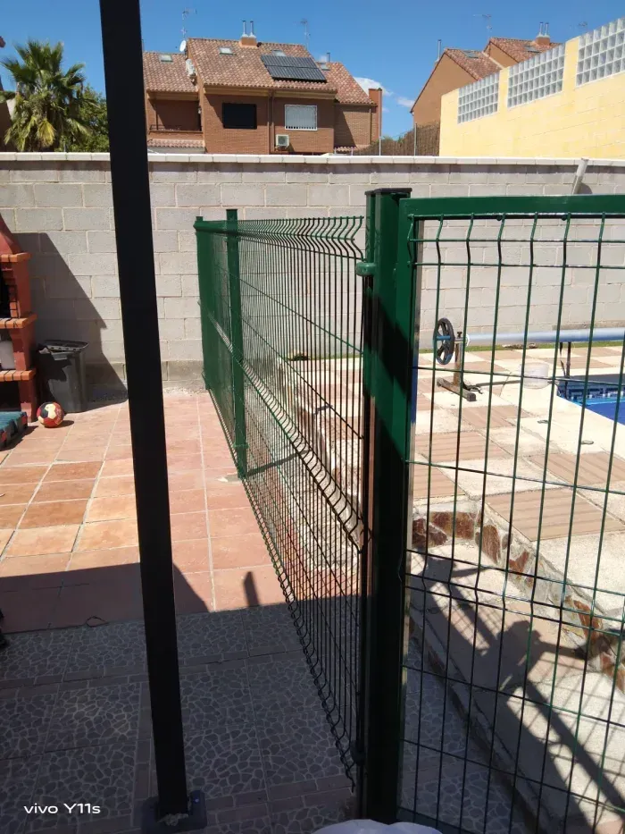 Una valla verde rodea una piscina.