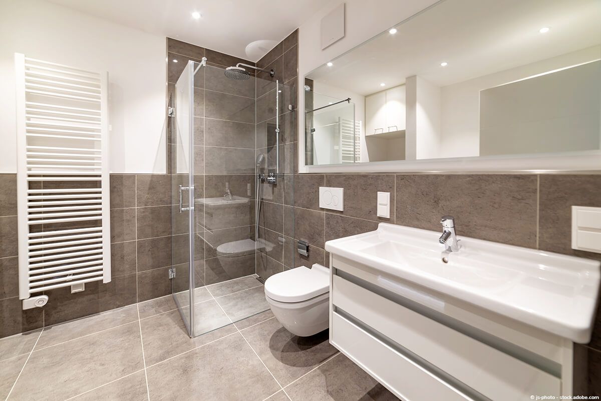 Modernes Badezimmer mit gefliesten Wänden und Boden, Dusche, Toilette, Waschbecken und Heizkörper.