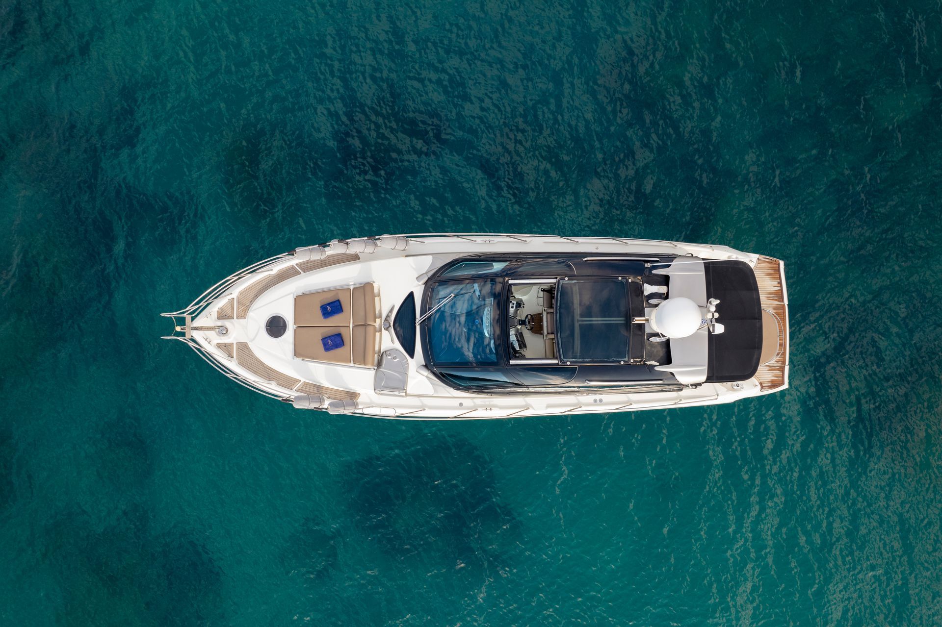 Aerial view of a white yacht floating on clear turquoise water