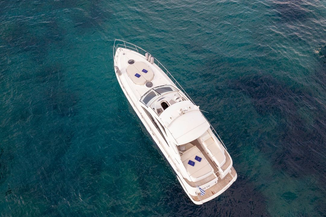 White yacht floating on clear blue water, viewed from above.