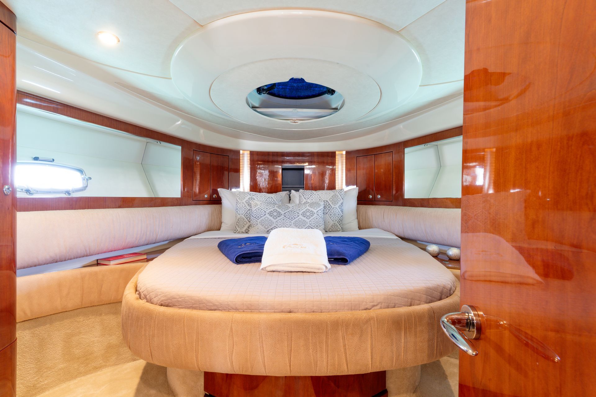 Luxurious yacht bedroom with round bed, wood paneling, mirrors, and ceiling skylight