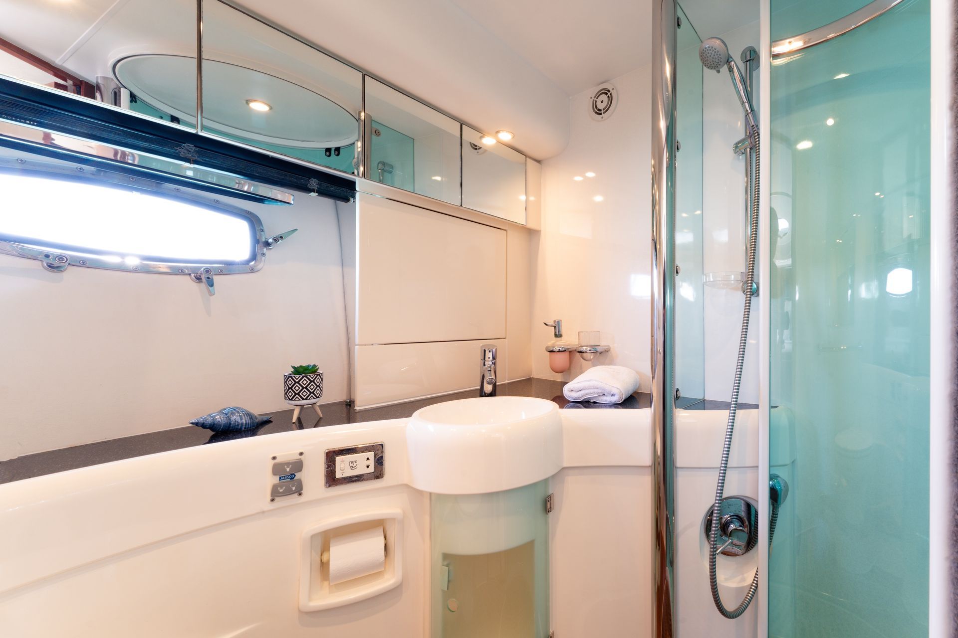 Compact modern bathroom with sink, mirror, glass shower, and teal accent walls