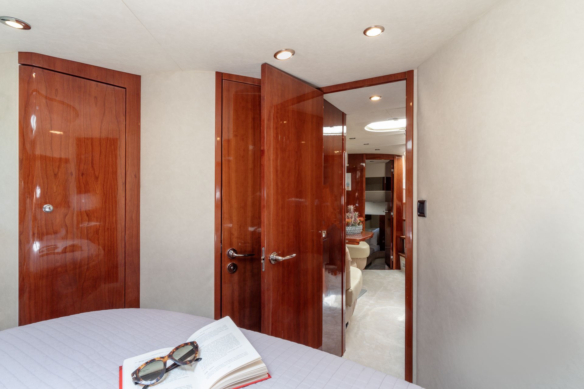 Bright bedroom with open wooden doors, mirrored closet, and a book on the bed.