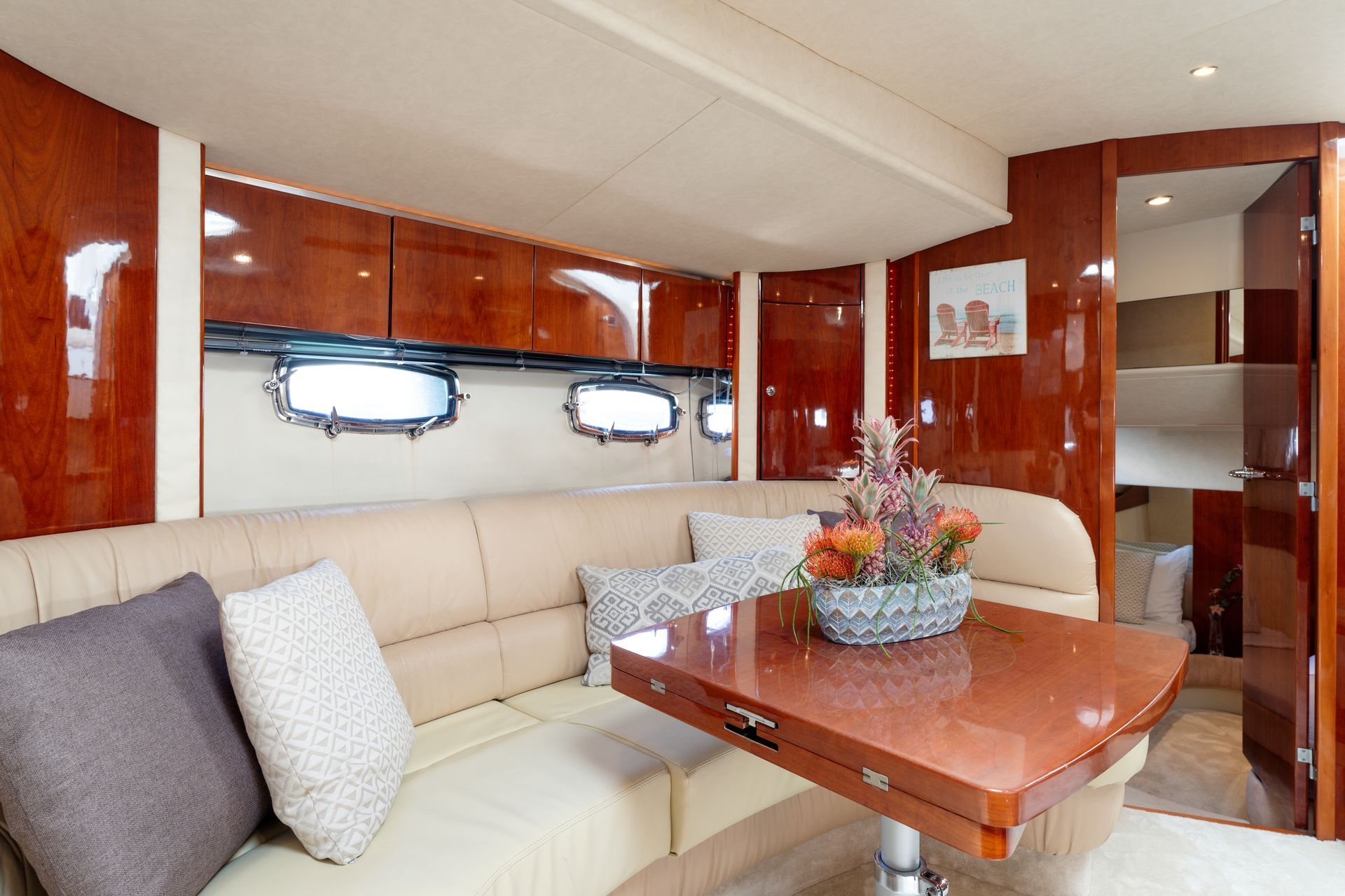 Elegant yacht salon with cream sectional, polished wood cabinets, and glossy dining table