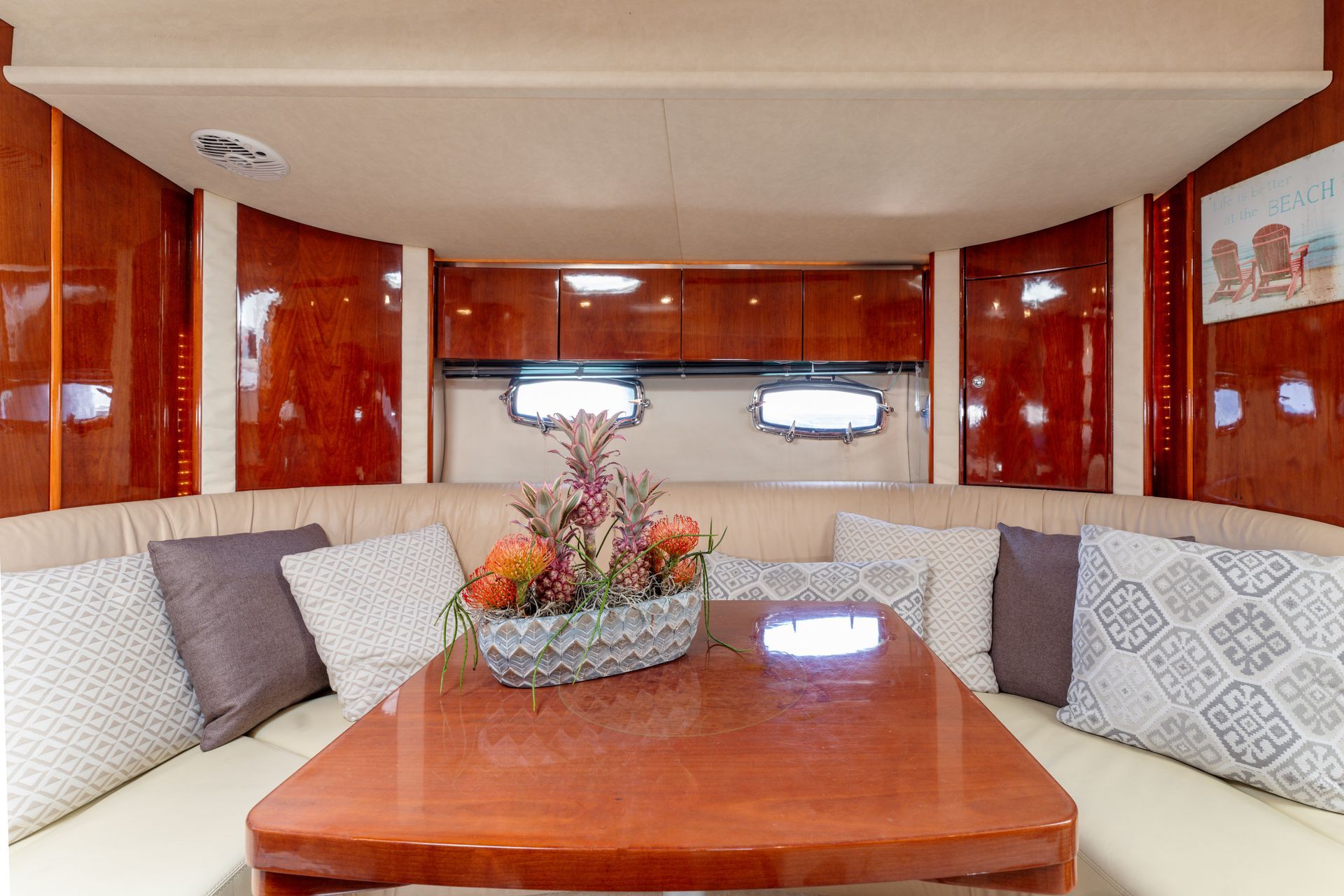 Luxury yacht salon with cream seating, polished wood table, and red wood-paneled walls
