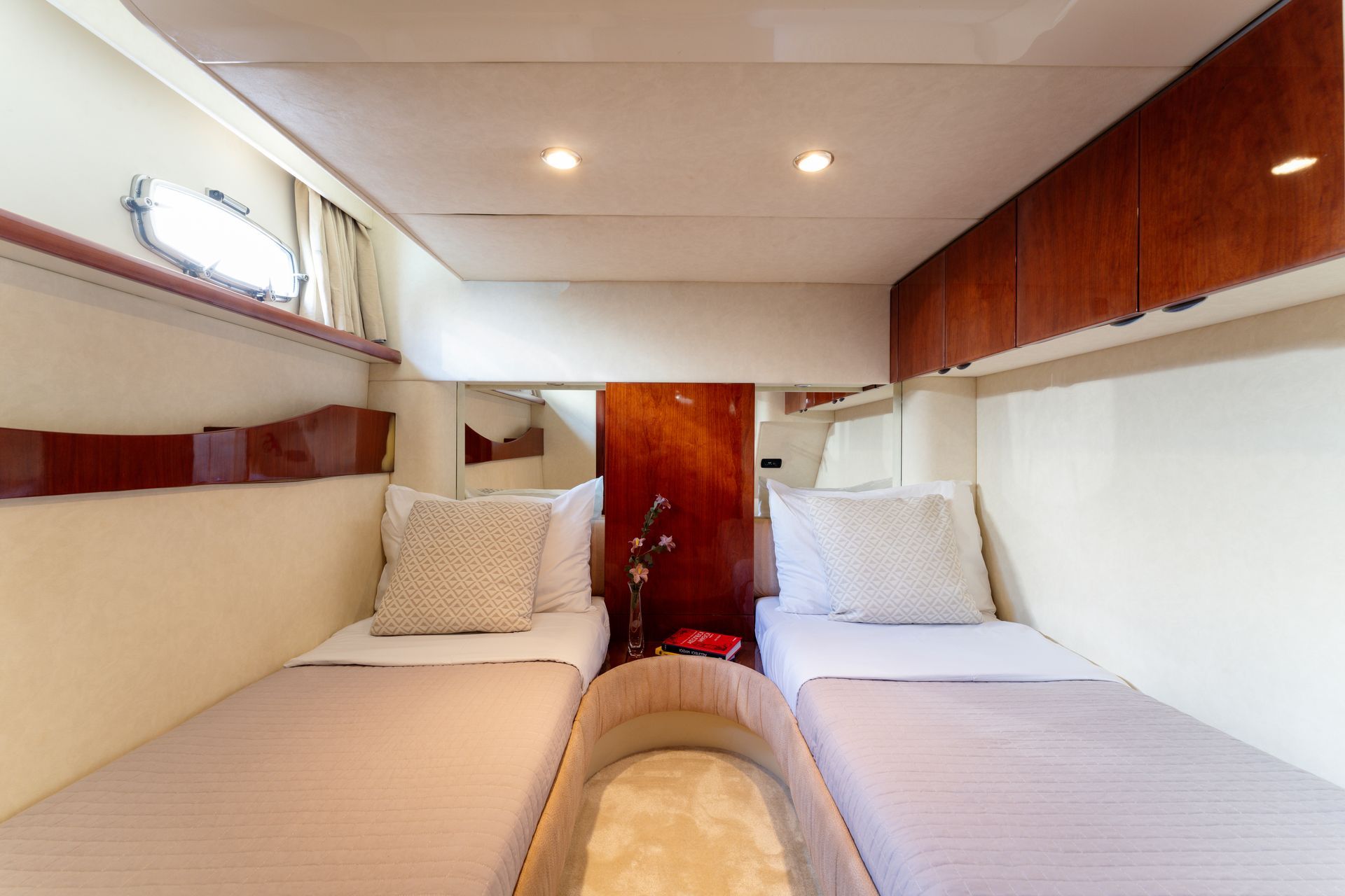 Twin beds in a compact cabin with wood cabinets, white walls, and a ceiling light