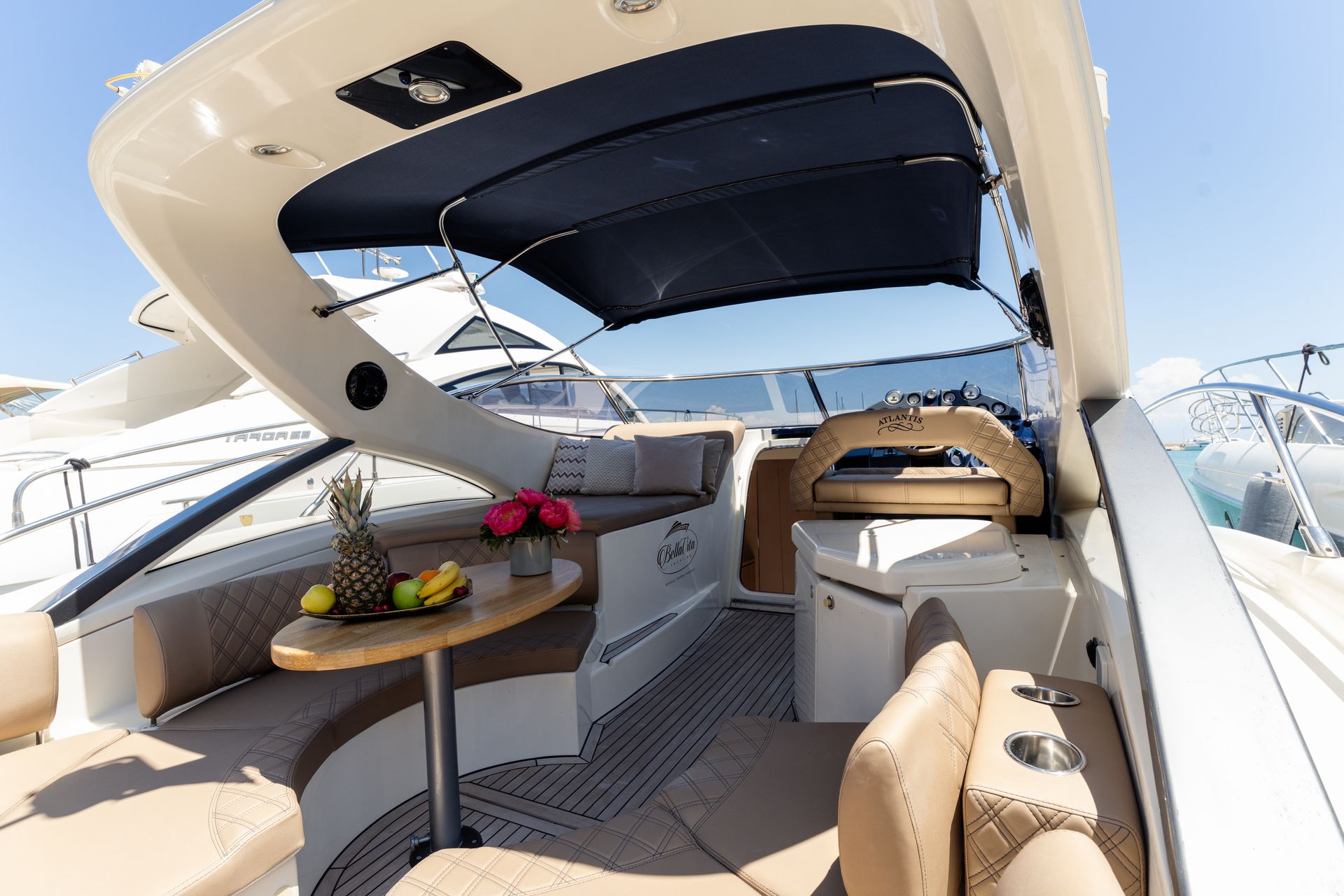 Luxury yacht cockpit with beige seating, a table, and a blue canopy under a bright sky