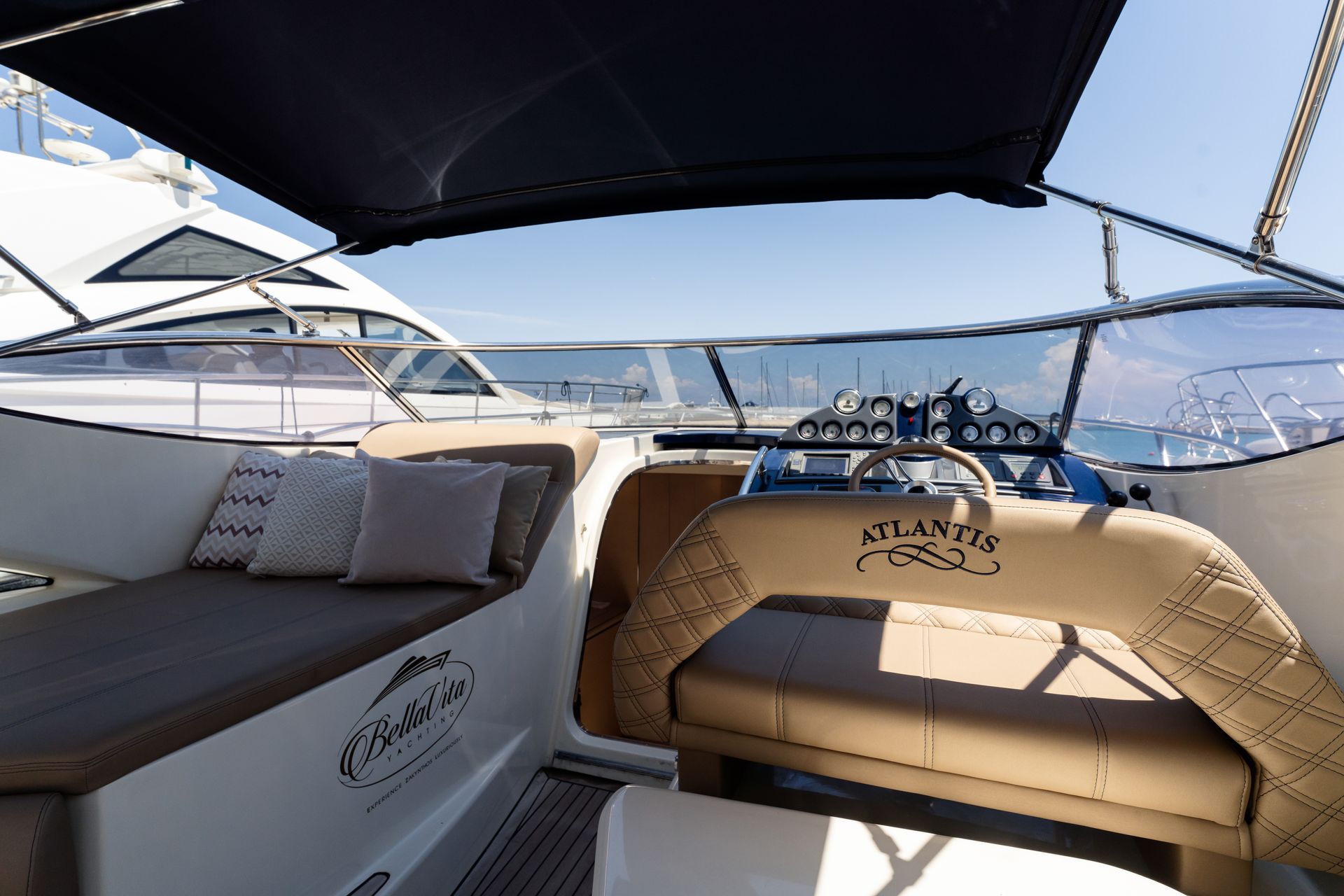Luxury yacht seating area with beige cushions, dark canopy, and ocean view at the stern