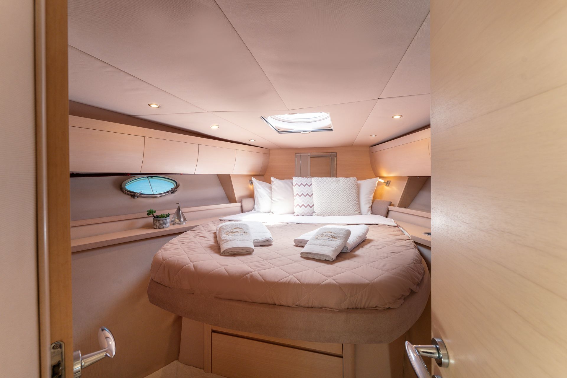 Cozy yacht cabin with a neatly made bed, white pillows, and warm beige wood paneling.