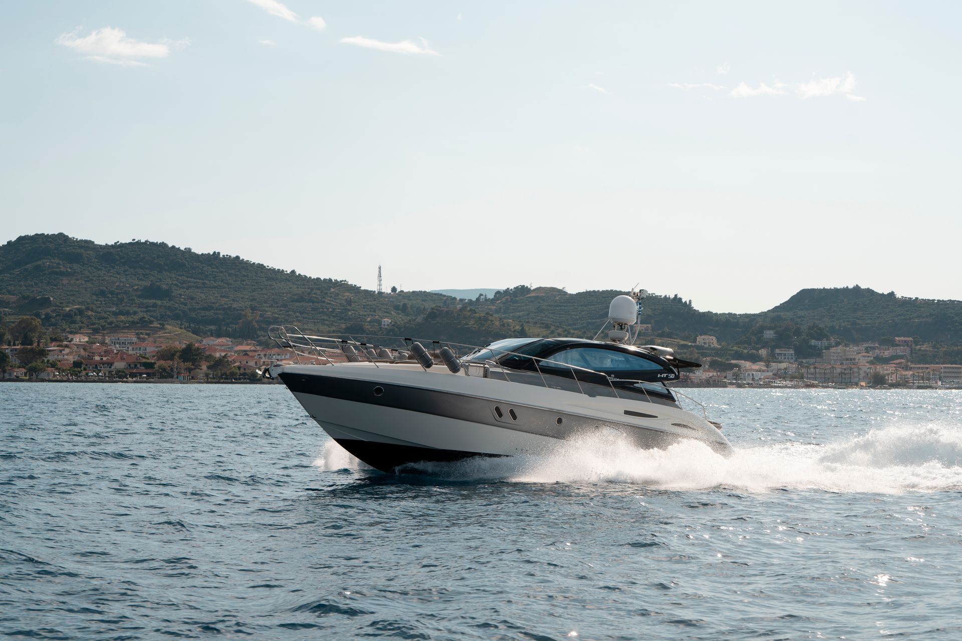 Speedboat cutting across choppy water with a hilly coastline in the background