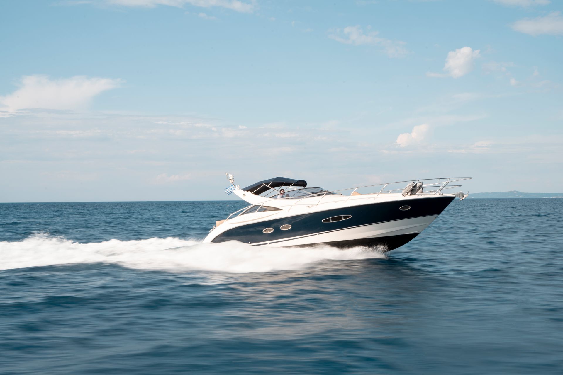 White speedboat skimming across blue water under a clear sky