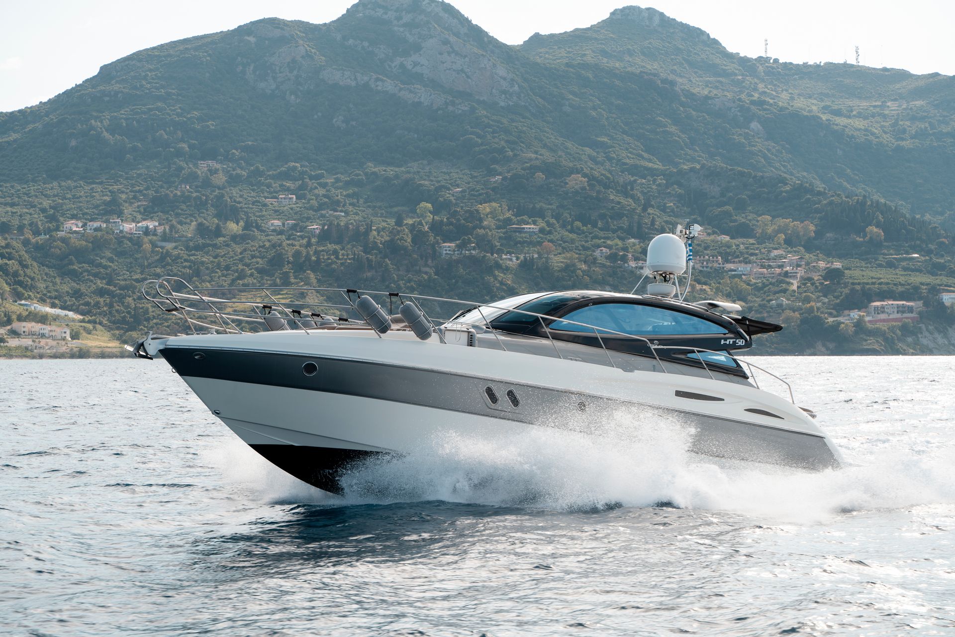 White speedboat skims over choppy water with mountains in the background
