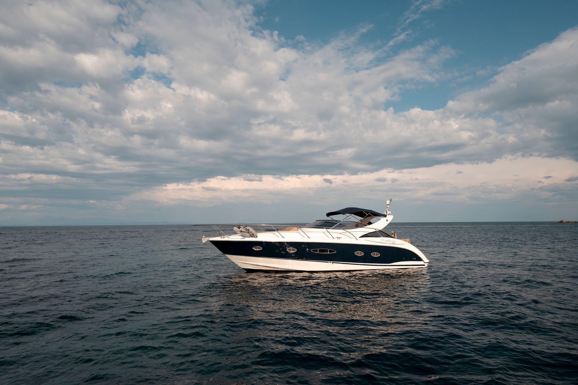 White and navy motor yacht on choppy sea under a cloudy sky