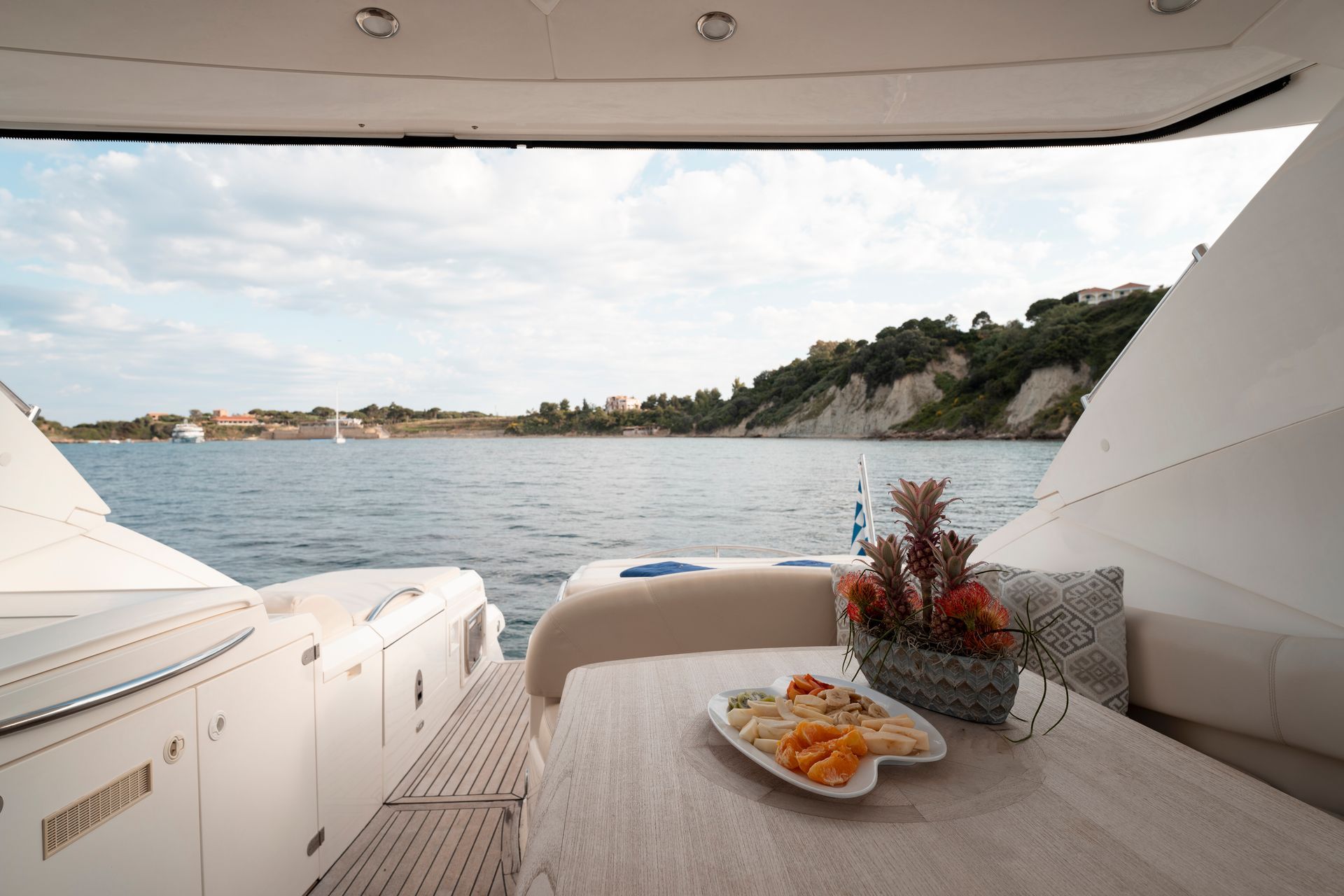 Yacht deck with table, tray of snacks, and sea view at sunset