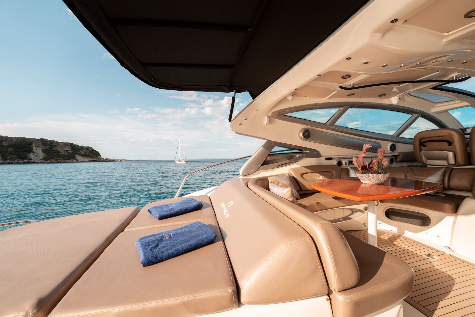 Luxury yacht deck with tan seating, blue cushions, and a calm sea view under a shaded canopy
