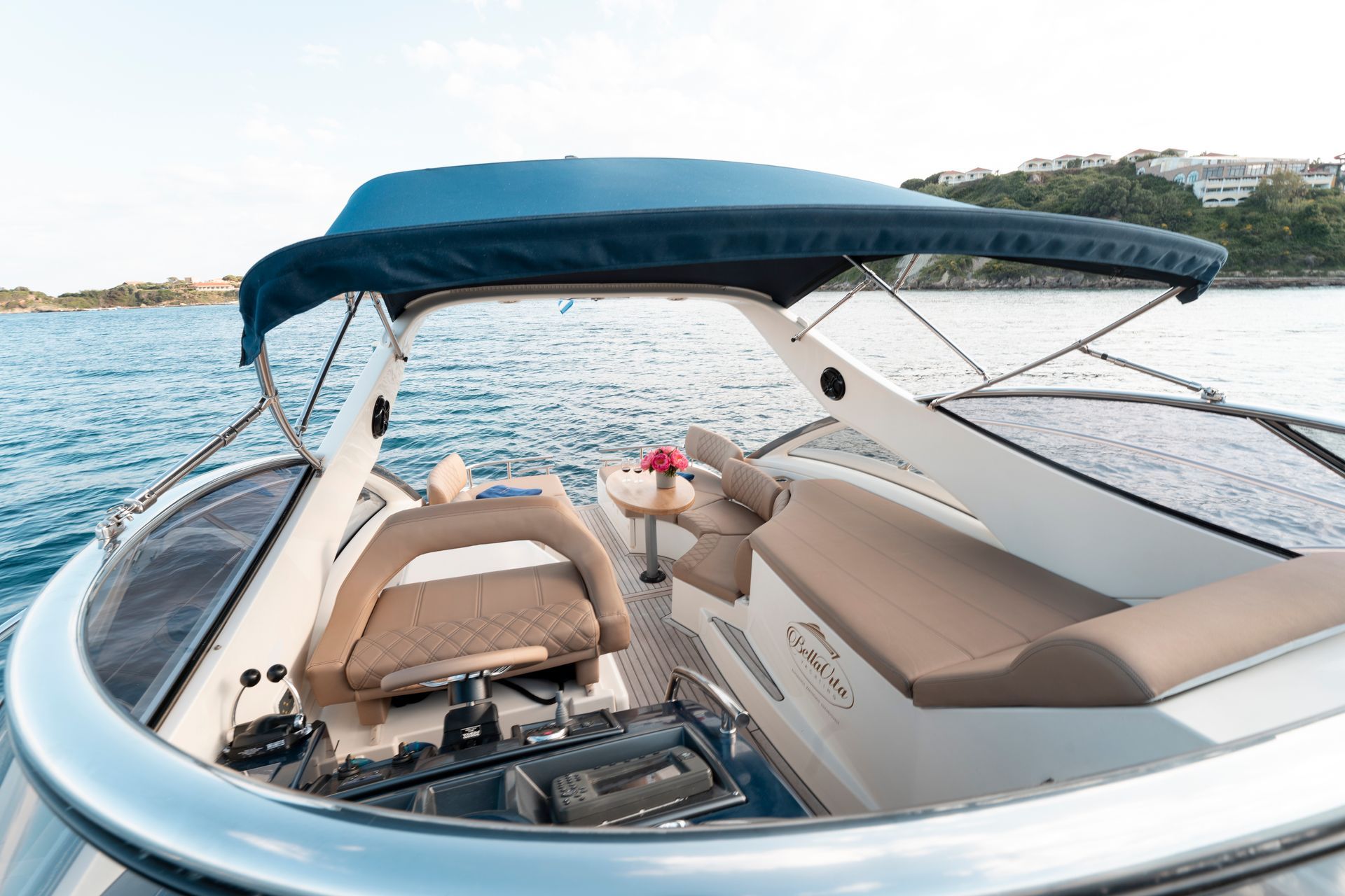 Boat cockpit with beige seats and blue canopy on calm water