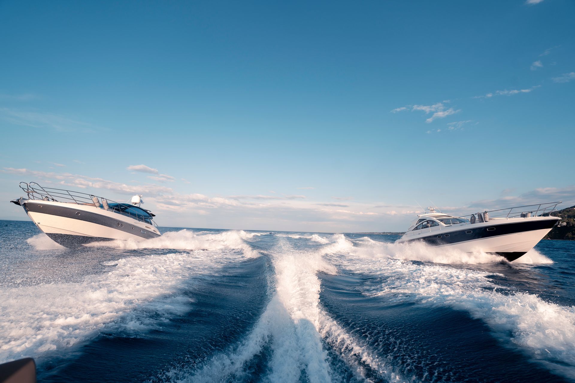 Two speedboats racing across choppy blue water under a bright sky
