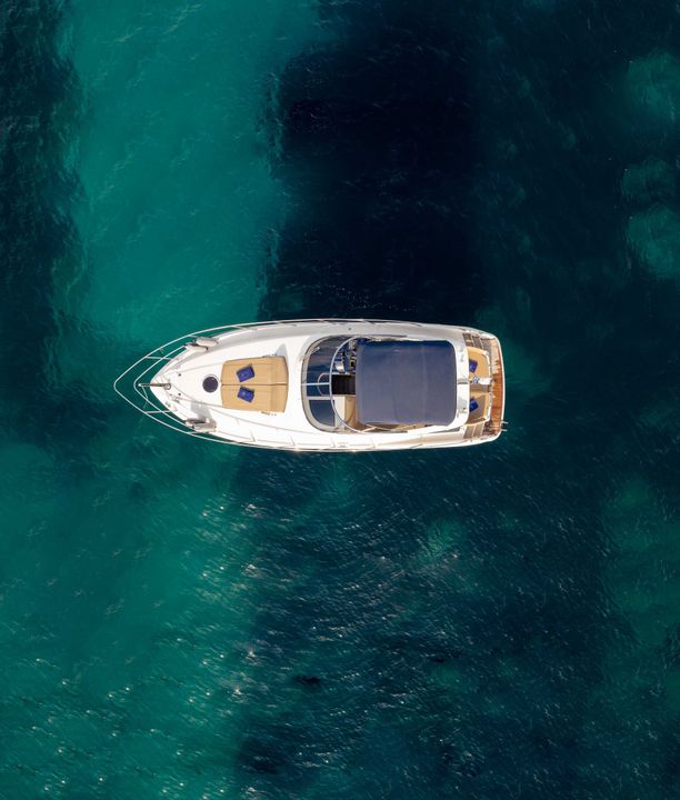 A white boat floating on clear turquoise water, viewed from above.