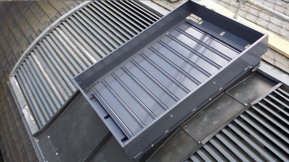 Cadre de ventilation ou de puits de lumière en métal gris sur un toit en tôle ondulée
