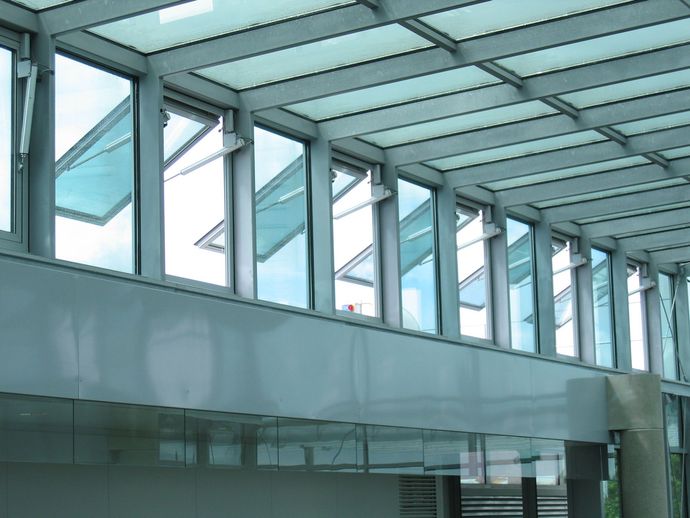 Intérieur d'un bâtiment moderne en verre et en acier, avec des rangées de fenêtres et un mur incurvé