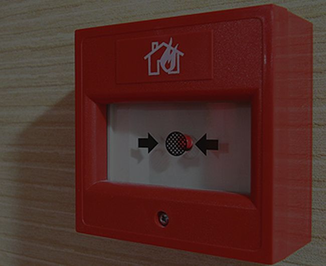 Déclencheur d'alarme incendie rouge avec bouton central mural.