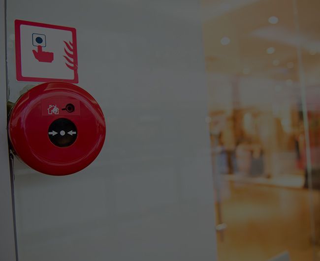 Déclencheur d'alarme incendie rouge fixé au mur près d'un couloir flou dans un bâtiment