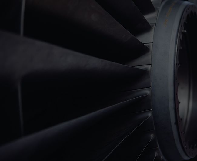 Gros plan sur les pales d'une turbine de moteur à réaction dans un intérieur métallique sombre.