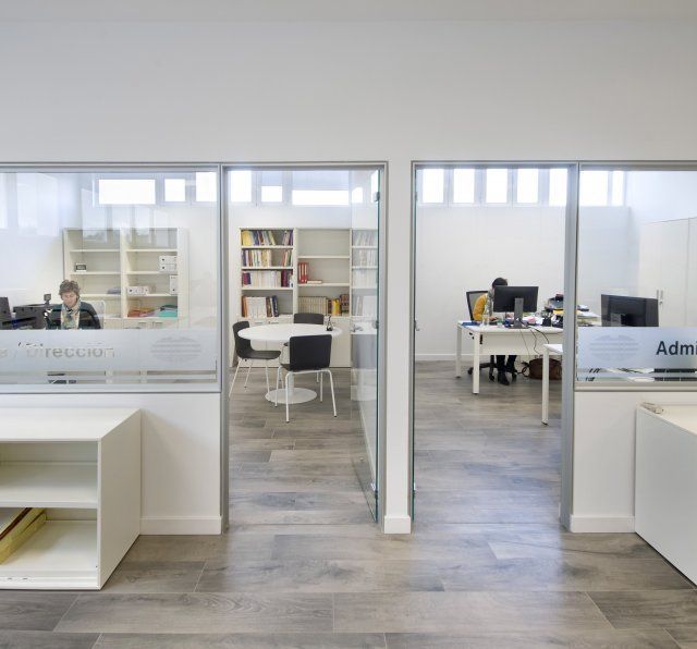 Una mujer se sienta en un escritorio en una oficina con un cartel que dice admin