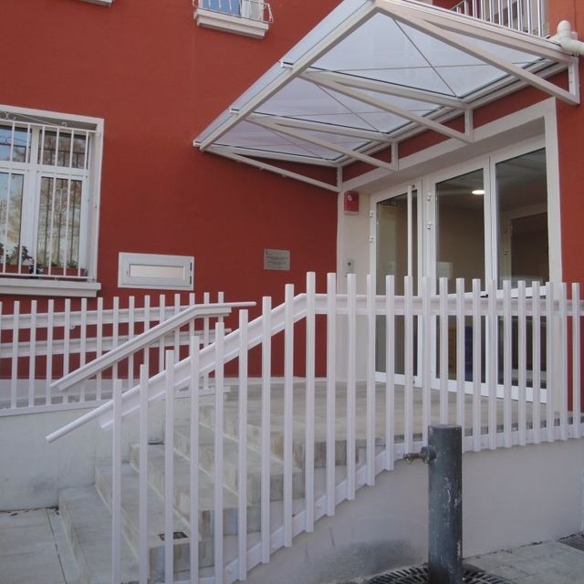 Un edificio rojo con una valla blanca y escaleras.