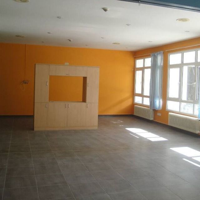 Una habitación vacía con paredes naranjas y ventanas blancas.