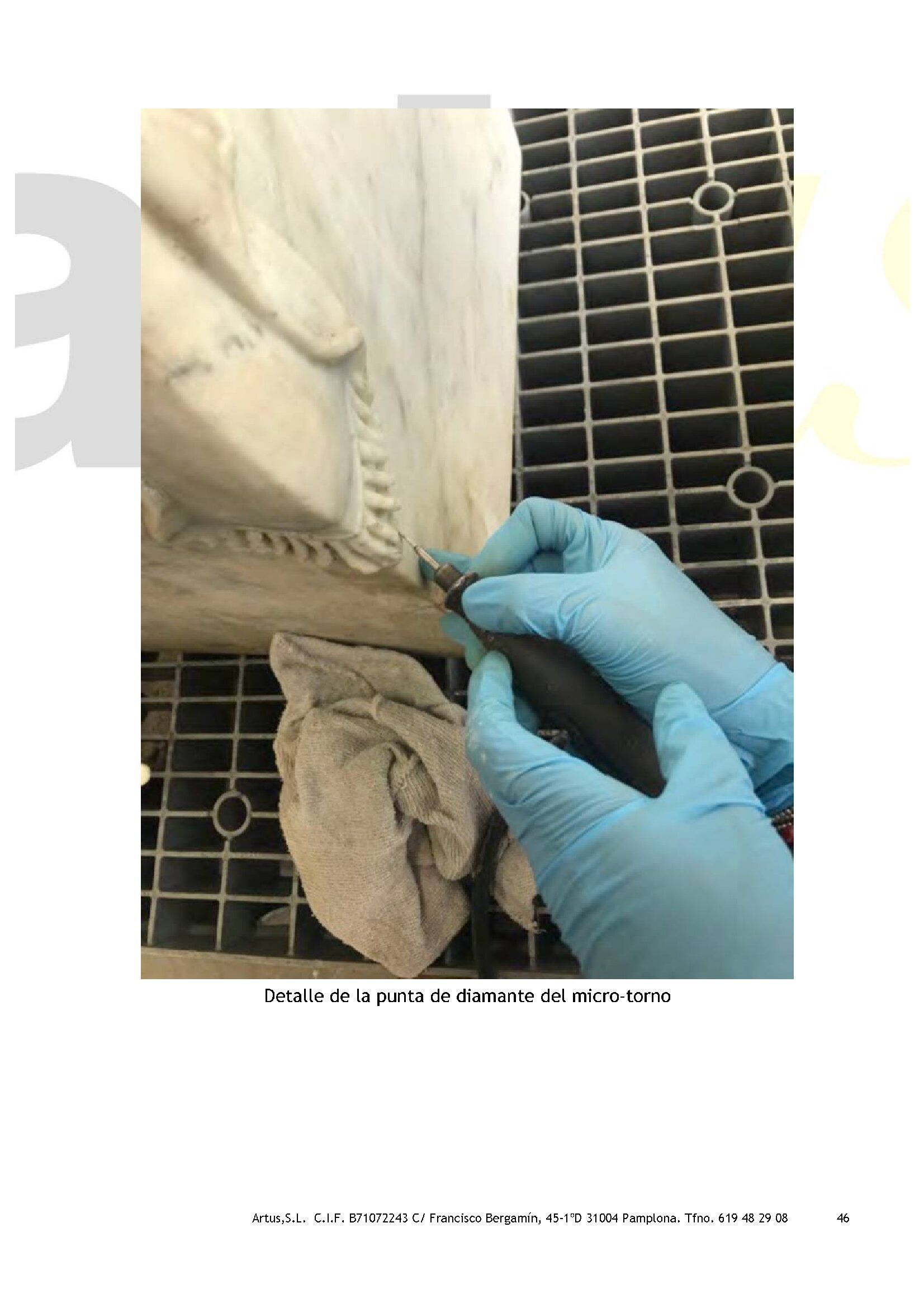 Una persona que lleva guantes azules está limpiando una estatua con una toalla.