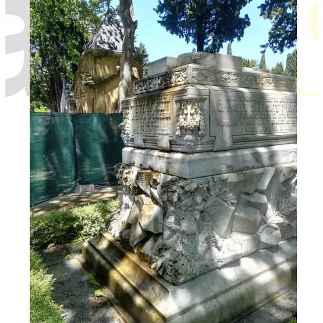 Una estatua en un parque con una valla verde al fondo.