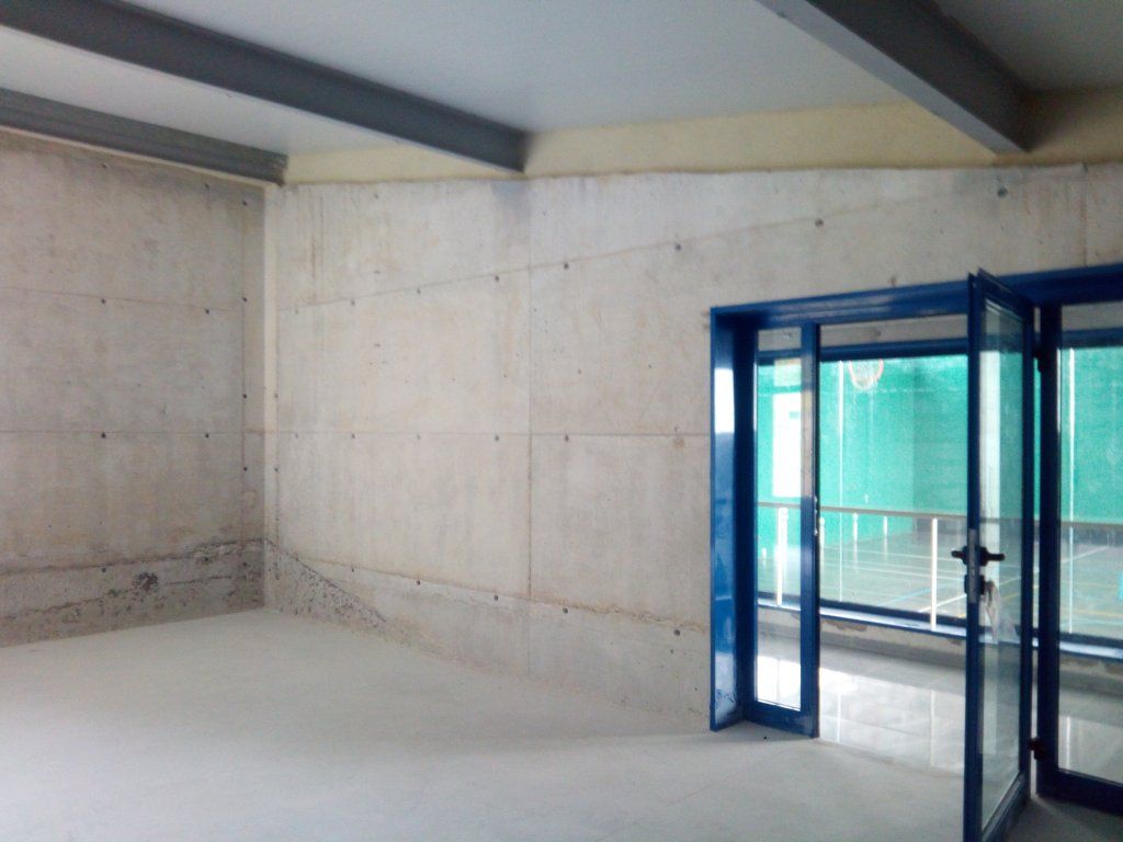 Una habitación vacía con una puerta azul y una pared de hormigón.