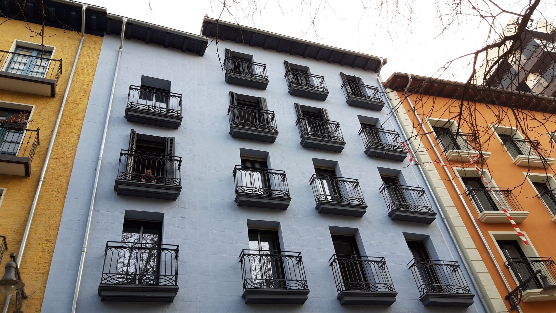Un hombre que lleva un casco y una máscara está usando un martillo para perforar un agujero en una pared.