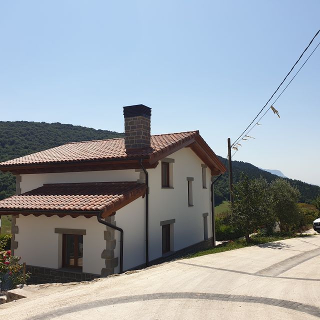 Una casa blanca con techo de tejas y chimenea
