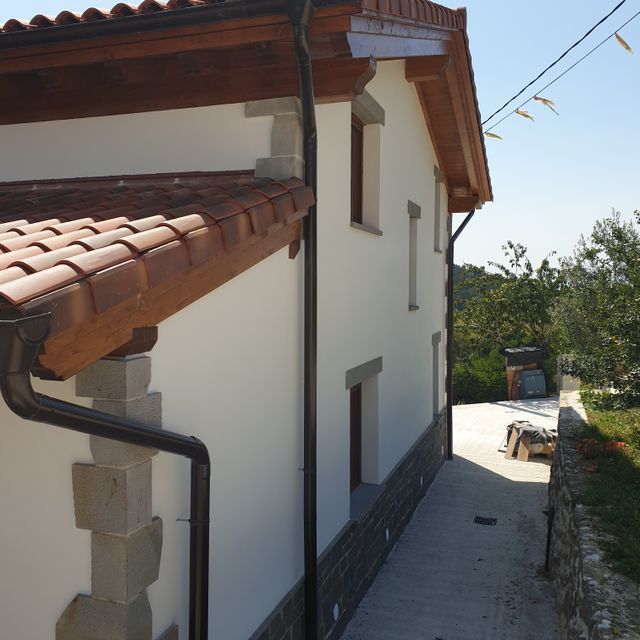 Una casa blanca con techo de tejas y canalones