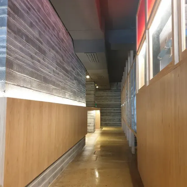 Un pasillo largo con una pared de ladrillo y paneles de madera.