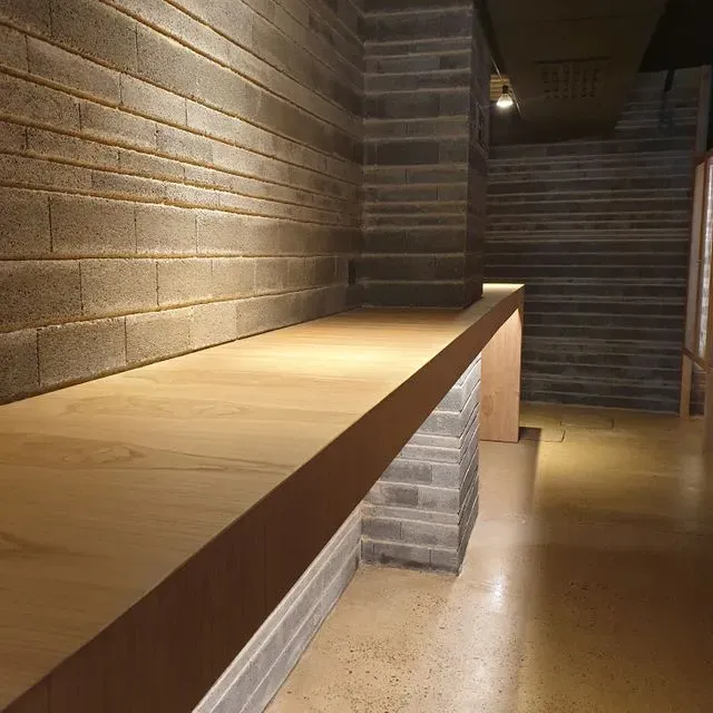 Una mesa larga de madera en un pasillo con paredes de ladrillo.