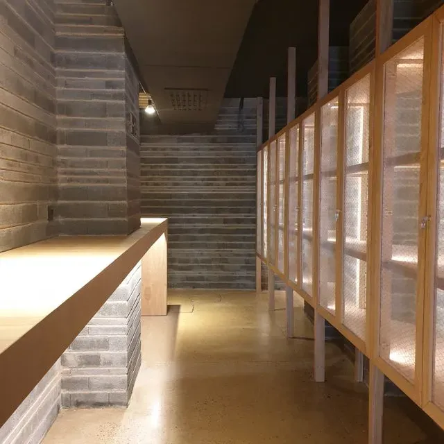 Un largo pasillo con una pared de ladrillos y estantes de madera.