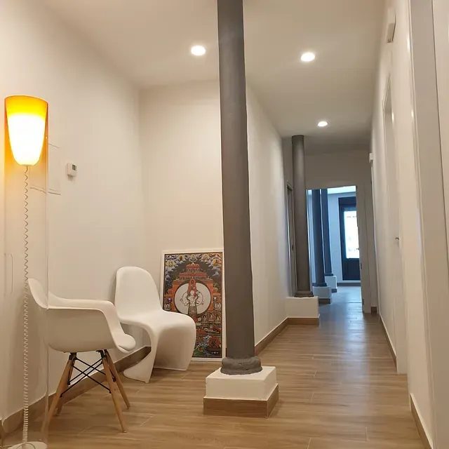 Un largo pasillo con sillas y una lámpara.