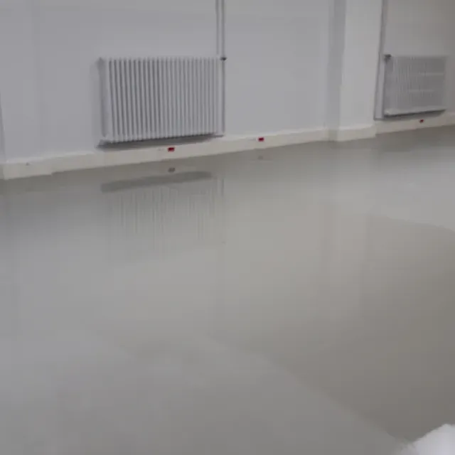 Una habitación con suelo blanco y un radiador en la pared.