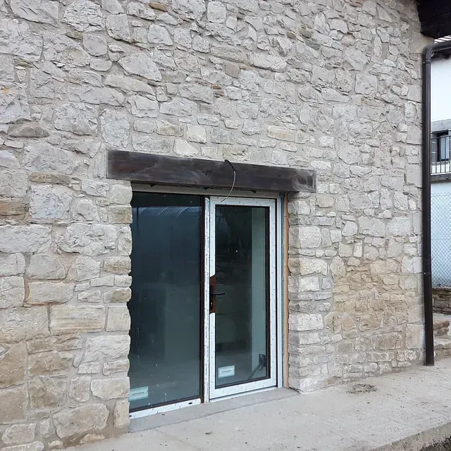 Un edificio de piedra con una puerta corrediza de vidrio