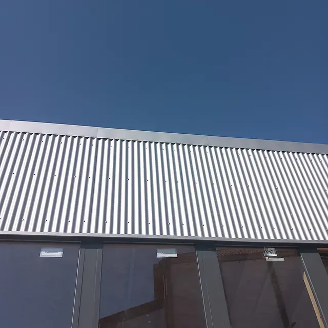 Un techo de metal corrugado blanco con un cielo azul de fondo.