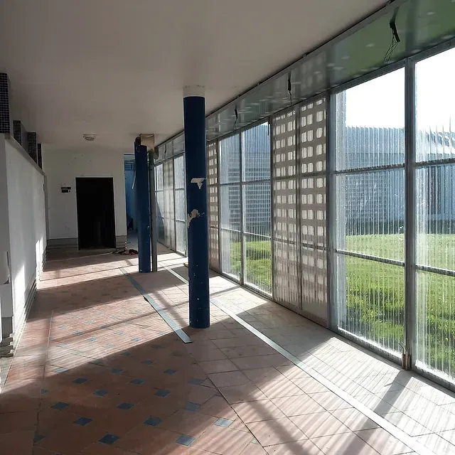 Un pasillo con muchas ventanas y un poste azul.