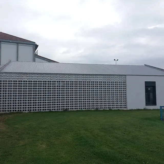 Un edificio blanco con techo gris está rodeado de césped verde.
