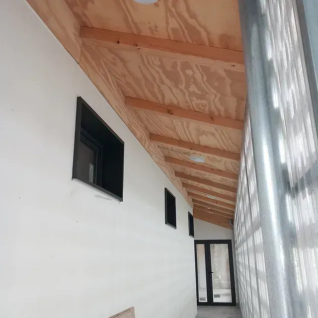Un largo pasillo con techo de madera y ventanas.