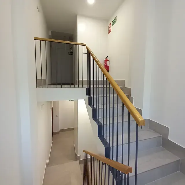 Un pasillo con escaleras y un extintor en la pared.
