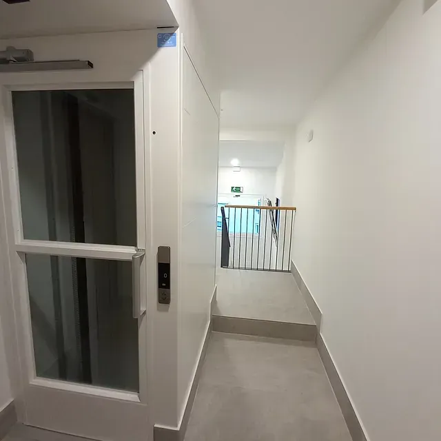 Un pasillo con una puerta de cristal que conduce a una escalera.