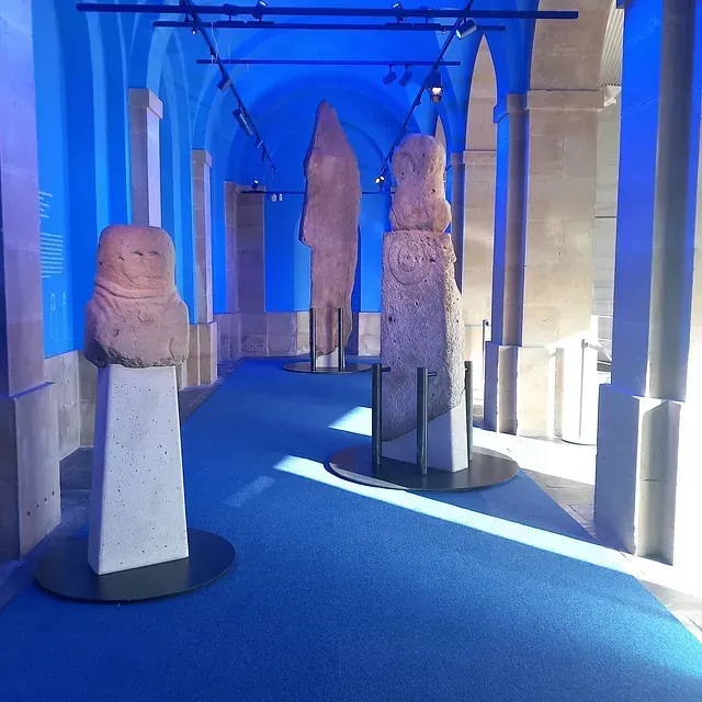 Un pasillo con paredes azules y estatuas en exhibición.